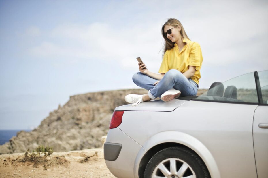 woman on top of a car texting